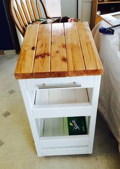 a wooden table sitting on top of a white shelf next to a bed and desk