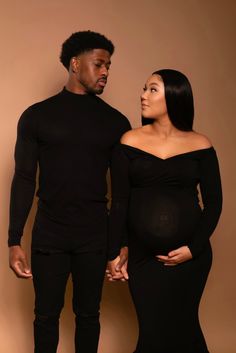 a man and woman standing next to each other in black outfits with their hands on their stomachs