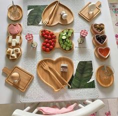 a white table topped with lots of wooden plates and bowls filled with different types of food