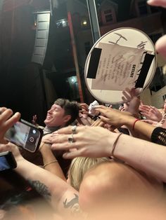 a group of people holding up their cell phones in front of a camera and taking pictures