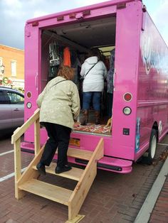 two women loading items into the back of a pink truck