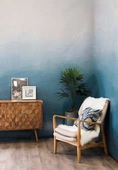 a blue painted room with a chair and potted plant on the floor next to it