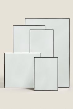 four square mirrors stacked on top of each other in front of a white wall and floor