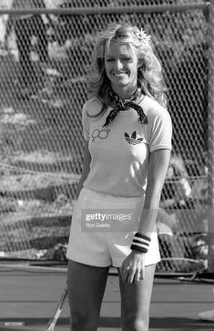 a woman holding a tennis racquet on top of a tennis court in front of a chain link fence