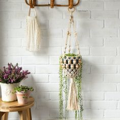 two macrame plant hangers on a white brick wall with potted plants