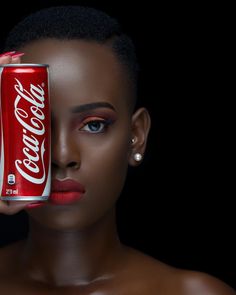 a woman holding a can of coca - cola in front of her face