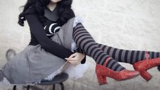 a woman sitting on top of a chair wearing high heels and tights with her legs crossed