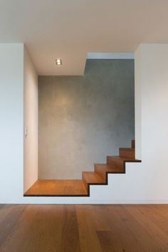 an empty room with wooden steps leading up to the ceiling and light fixture on the wall