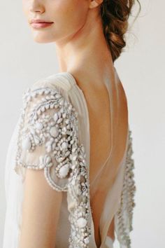 a woman in a white dress with pearls on her head and shoulders, looking off to the side