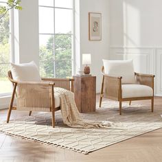 a living room with two chairs and a rug on the floor in front of windows