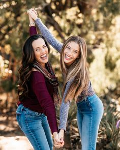 two young women holding hands and smiling at the camera