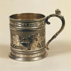 an antique silver mug with horses and riders on it