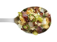 a close up of a spoon with food in it on a white background, including broccoli and other vegetables