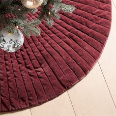 a christmas tree with ornaments on it and a red round rug in front of it