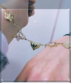 a person wearing a gold bracelet with hearts and flowers on the chain that is attached to their wrist