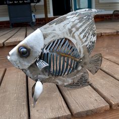 a metal fish sculpture sitting on top of a wooden deck