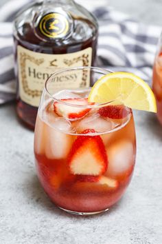 a close up of a drink in a glass with strawberries and lemon wedges