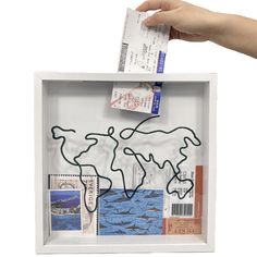 a hand holding a piece of paper over a box filled with stamps and postcards