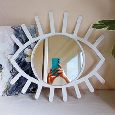 a person taking a selfie in front of a mirror with an eye shaped frame