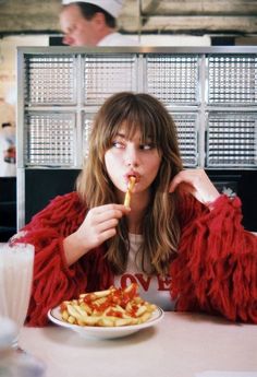 a woman sitting at a table eating french fries