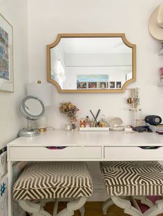 a white desk with two stools and a mirror on the wall in front of it