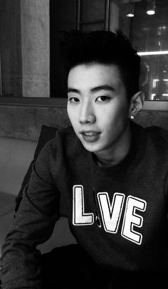 black and white photograph of a young man with short hair wearing a love sweatshirt sitting on a couch