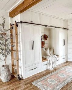 a room with white cupboards and wooden flooring, including a rug on the floor
