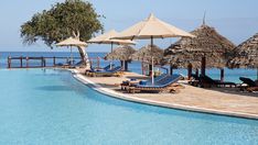 an outdoor swimming pool with lounge chairs and umbrellas next to the water's edge