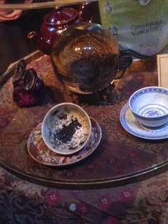 a table topped with plates and bowls on top of a wooden table next to a glass vase