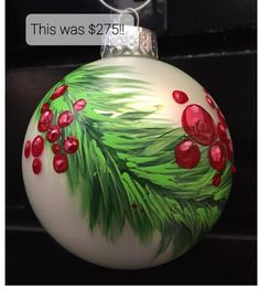 a glass ornament with red berries and green leaves on it's side