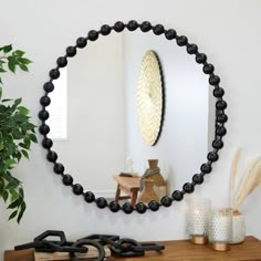 a mirror on the wall above a table with candles and vases next to it