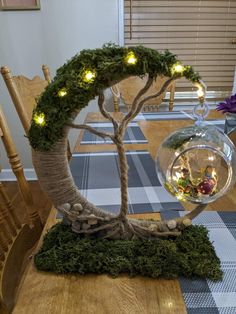 a table topped with a glass bowl filled with water and lights next to a tree