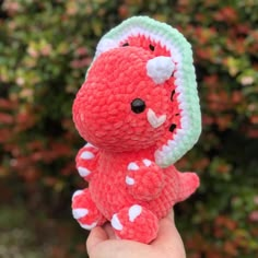 a small crocheted red and green stuffed animal with white dots on it's face