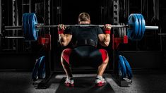 a man is squatting down while holding a barbell