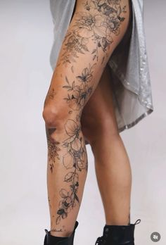 a woman's legs with tattoos on them and flowers all over the leg area