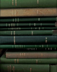 a stack of green books sitting next to each other on top of a wooden table