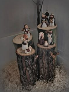 several figurines are sitting on logs in the hay next to a tree stump