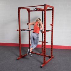 a woman is doing squats on a pull - up machine in a gym area