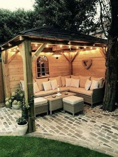 an outdoor living area with couches and lights on the roof, surrounded by trees