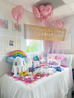 a table topped with lots of balloons and other items next to a sign that says welcome to this family