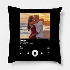 a black pillow with an image of a man and woman kissing on the beach at sunset