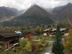 the mountains are covered in clouds and trees, while houses stand on either side of them