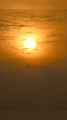 the sun is setting over the ocean with two surfers in the foreground and an airplane on the far side