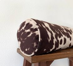 a brown and white pillow sitting on top of a wooden stool