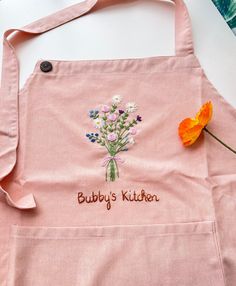 a pink apron with embroidered flowers on it