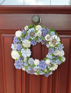 a wreath is hanging on the front door with blue and white flowers in it's center