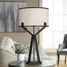 a table lamp sitting on top of a wooden table next to a white couch in a living room