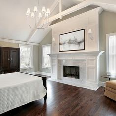 a large bedroom with a fireplace and white furniture