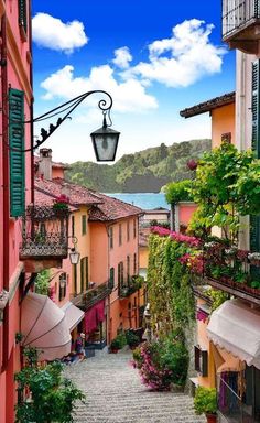 an alley way with lots of colorful buildings and flowers on the sides, along with a lamp post