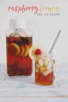 a pitcher filled with liquid next to a cup full of tea and sliced fruit on the side